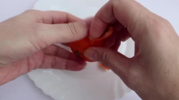 Hands clean the mandarin from the peel.  - Video