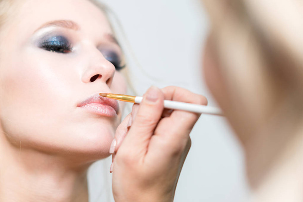 Makeup. Makeup artist performs lip makeup. Close-up - Фото, изображение