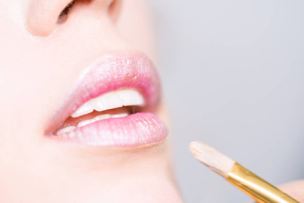 Lips close up. Makeup artist applies pink lipstick - Φωτογραφία, εικόνα