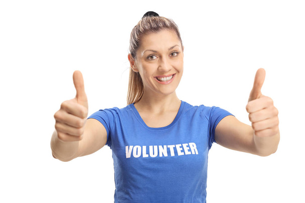 Young female volunteer showing thumbs up and smiling at the camera isolated on white background - Photo, Image