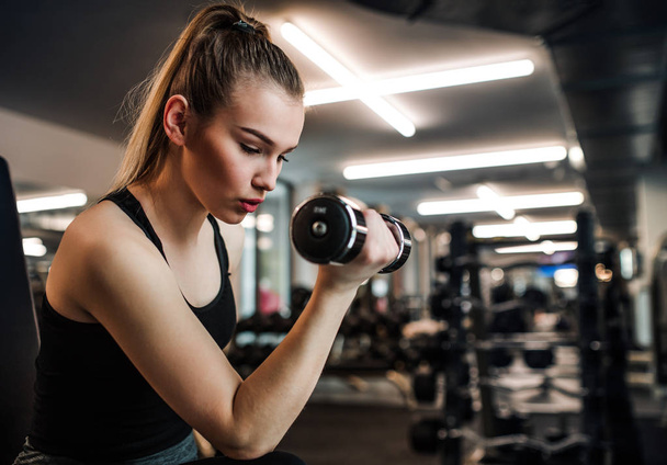 Young girl or woman with dumbbells, doing workout in a gym. - Foto, imagen