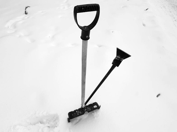 Snow shovel and ice ax stuck in the snow in winter - Фото, зображення