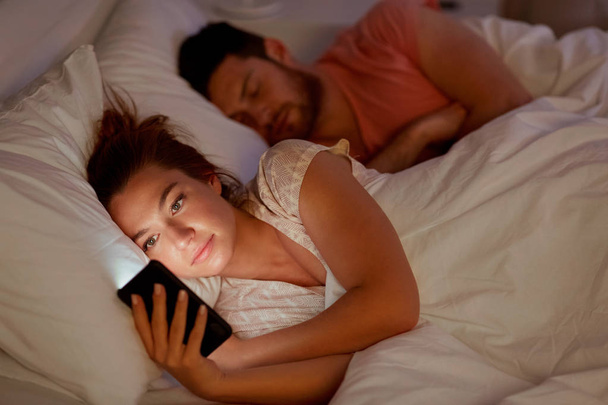 woman using smartphone while boyfriend is sleeping - Foto, Imagem