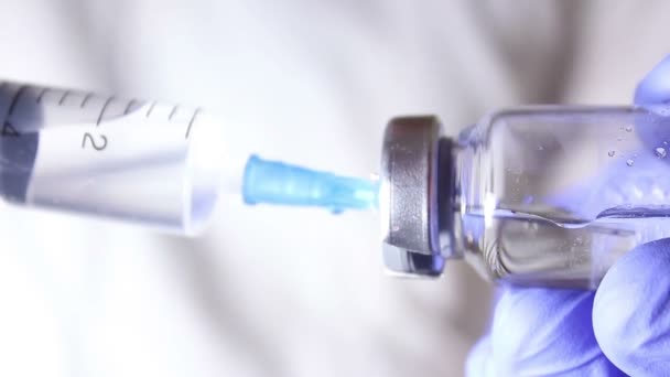 Doctors hands fill the syringe with vaccine, preparing for the injection of the injection to the patient. - Video, Çekim