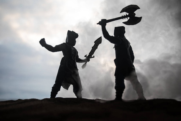 Medieval battle scene artwork decoration with toys. Silhouettes of figures as separate objects, fight between warriors on sunset foggy background. Selective focus - Photo, Image