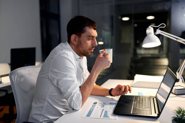 businessman with coffee and laptop at night office - Φωτογραφία, εικόνα
