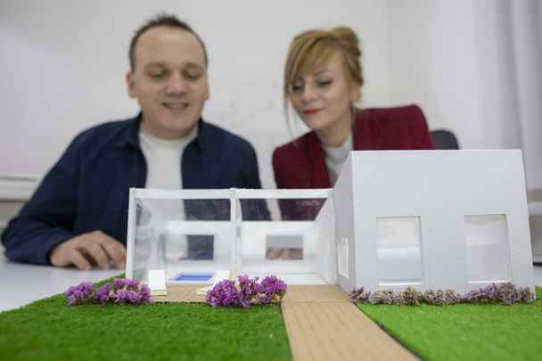 Два архитектора смотрят на образцовый дом в офисе
 - Фото, изображение