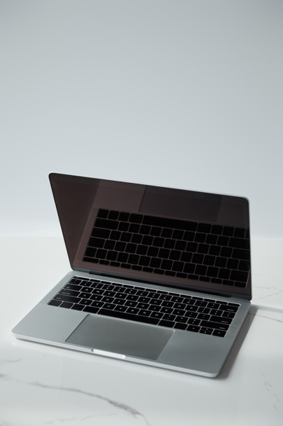 ноутбук с черной клавиатурой и пустой экран на белой поверхности изолированы на сером
 - Фото, изображение
