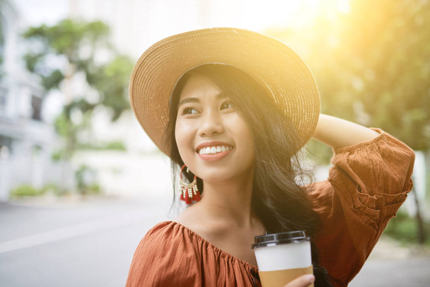 Portrait of beautiful smiling woman in straw hat walking in streets on sunny day - Photo, image