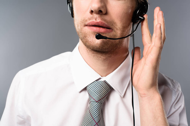 cropped view of serious call center operator touching headset  - Fotografie, Obrázek