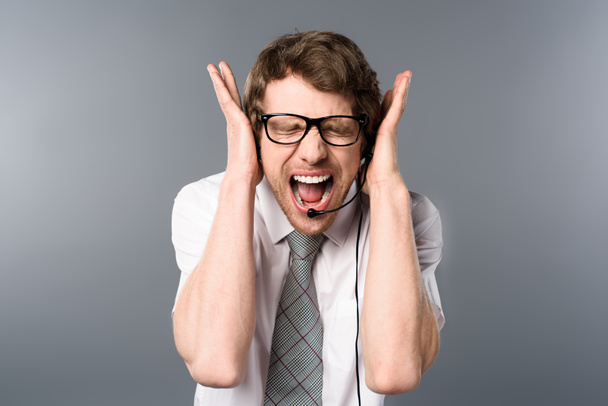 θυμωμένος κλήση κέντρο χειριστής στα ακουστικά και γυαλιά ουρλιάζοντας με τα χέρια στα αυτιά - Φωτογραφία, εικόνα