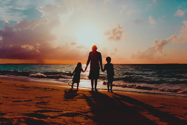 isä ja kaksi lasta kävelemässä rannalla auringonlaskun aikaan
 - Valokuva, kuva