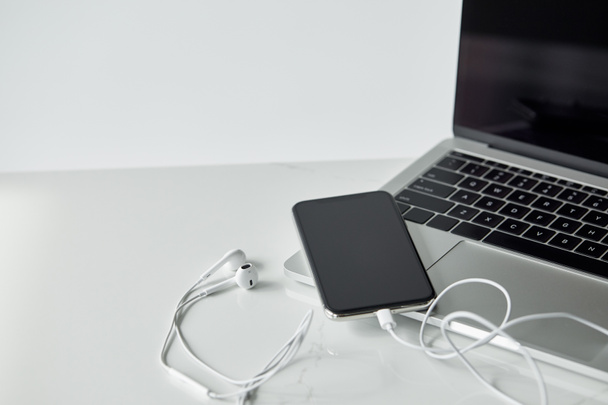 laptop and smartphone with connected earphones isolated on grey - Foto, imagen