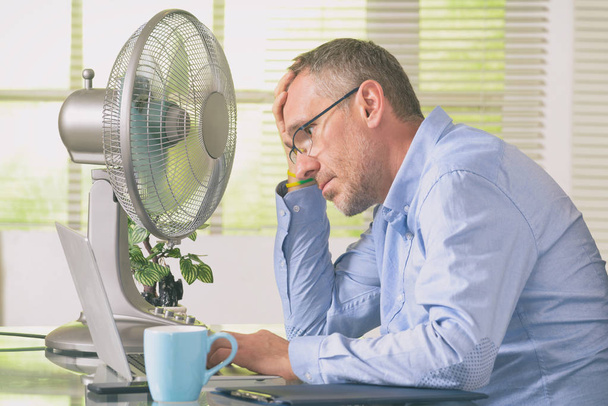 Человек страдает от жары в офисе или дома
 - Фото, изображение