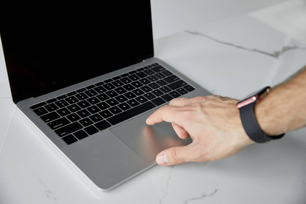 beyaz mermer yüzeyde laptop kullanarak akıllı saat adam kısmi görünümü - Fotoğraf, Görsel