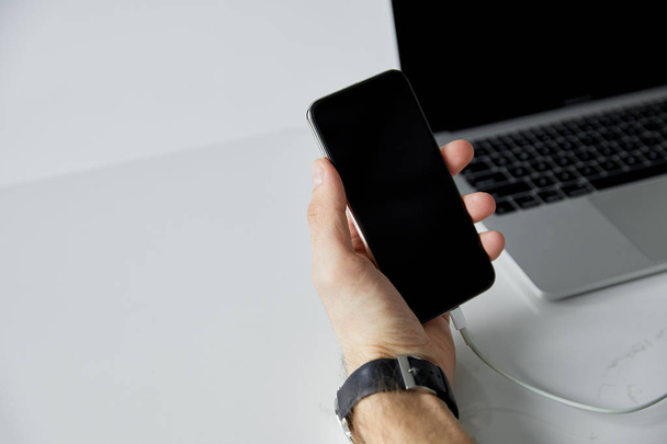 cropped view of man holding smartphone with blank screen and laptop isolated on grey - Foto, Bild