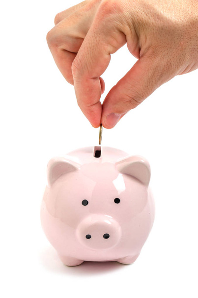Man hand puts a coin in a pink piggy Bank. - Photo, image