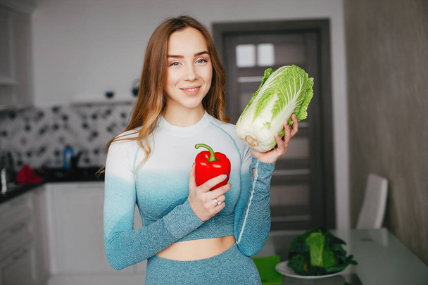Sports girl in a kitchen with vegetables - Φωτογραφία, εικόνα