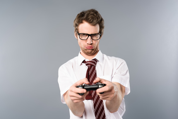 Aufgebrachter Geschäftsmann spielt Videospiel mit Steuerknüppel auf grauem Hintergrund - Foto, Bild
