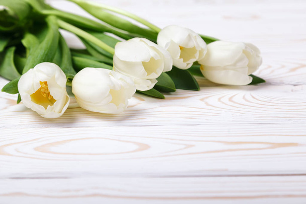 Beautiful composition with white tulips on white wooden background. Spring still life, soft focus, place for text - Fotó, kép