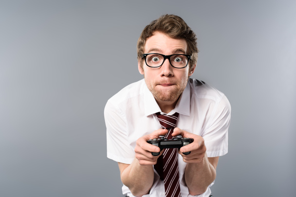 Konzentrierter Geschäftsmann spielt Videospiel mit Steuerknüppel auf grauem Hintergrund - Foto, Bild