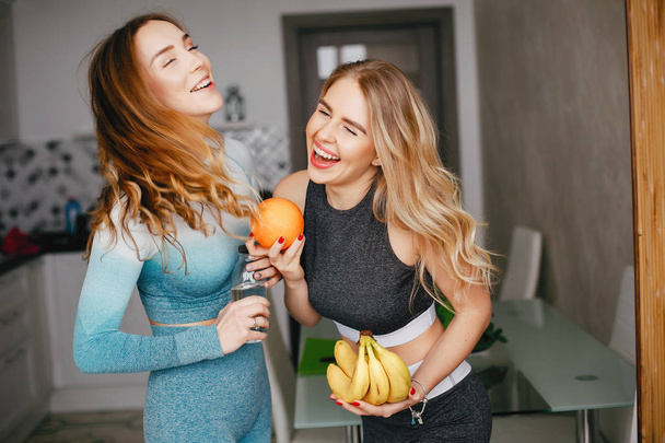 Two sports girl in a kitchen with vegetables - Foto, immagini