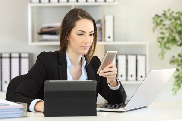Busy businesswoman using multiple devices at office - Foto, afbeelding