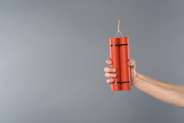 cropped view of man holding dynamite on grey background - Photo, Image