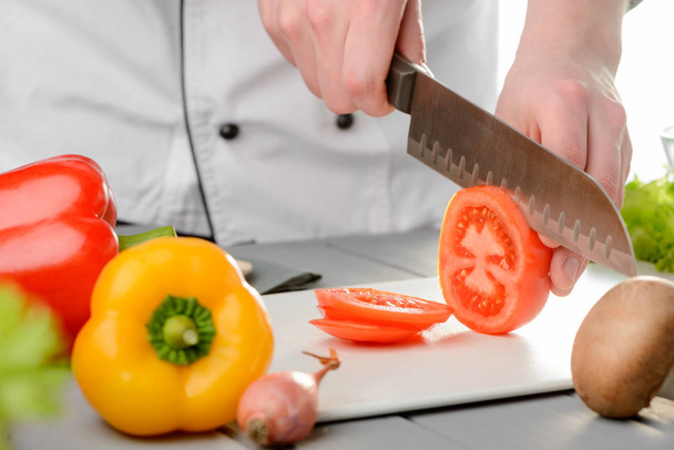 Chef cutting a tomato - Foto, afbeelding