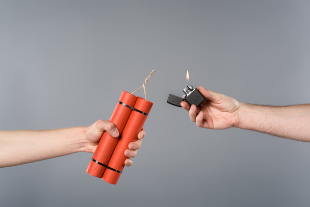 cropped view of men holding dynamite and lighter on grey background - Photo, Image