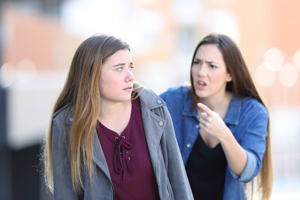 Angry girl scolding her confused friend in the street - Foto, imagen