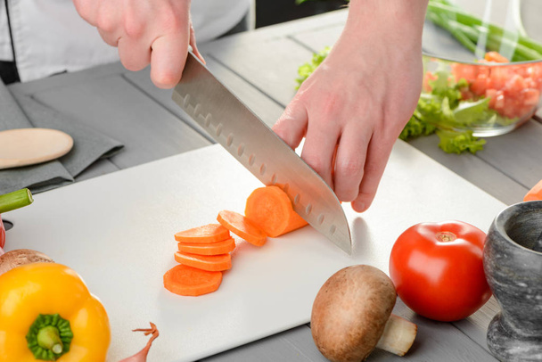 Mans cutting a carrot - Фото, изображение