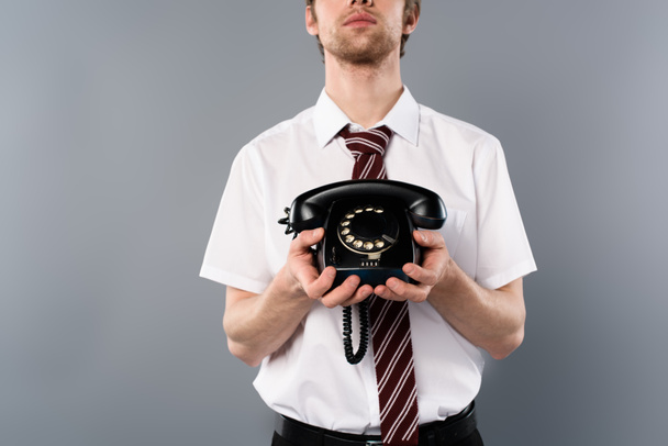 cropped view of businessman holding vintage phone on grey background - 写真・画像