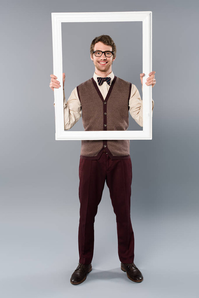 happy man holding white frame on grey background - Foto, Bild