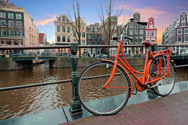 Bicicleta naranja a lo largo de los canales en Amsterdam Holanda
 - Foto, imagen