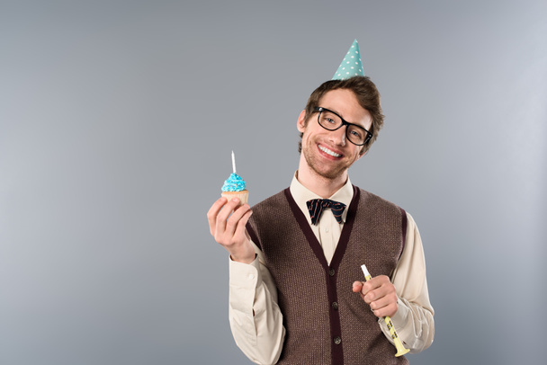 усміхнений чоловік в окулярах і вечірня кепка тримає кекс зі свічкою
  - Фото, зображення