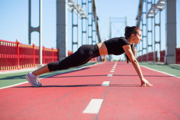Full length side view of a lovely athletic woman on a plank posi - 写真・画像