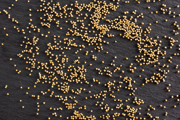White mustard seeds on grey stone - Foto, afbeelding