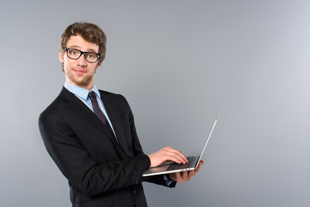 funny businessman in suit using laptop on grey background - Fotoğraf, Görsel