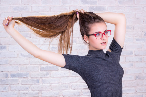 Jeune fille en lunettes rouges tire vers le haut de ses cheveux longs
 - Photo, image