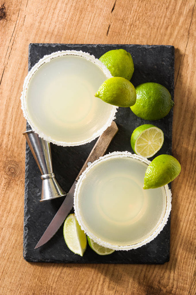 Margarita-Cocktails mit Limette im Glas auf einem Holztisch. Ansicht von oben - Foto, Bild