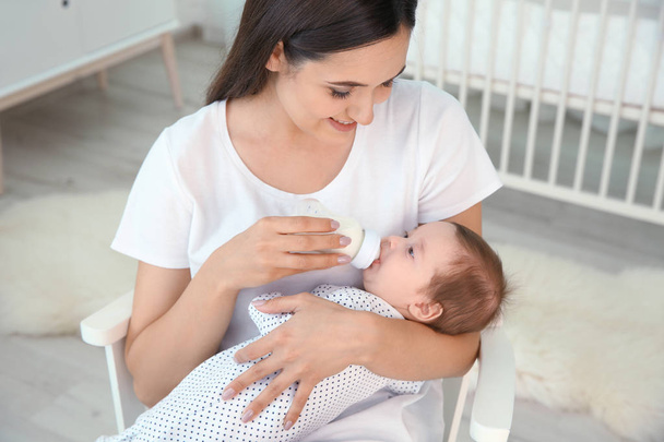 Woman feeding her baby from bottle at home - Foto, Bild
