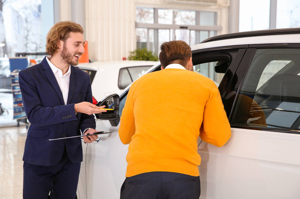Car salesman working with customer in dealership - Φωτογραφία, εικόνα