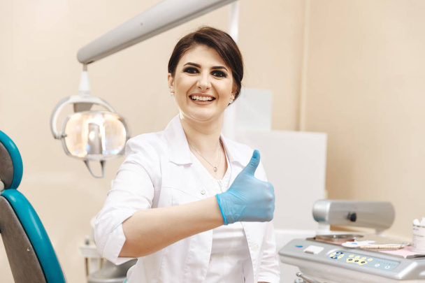 Foto de primer plano del dentista femenino en la sala dental que muestra el pulgar
. - Foto, Imagen