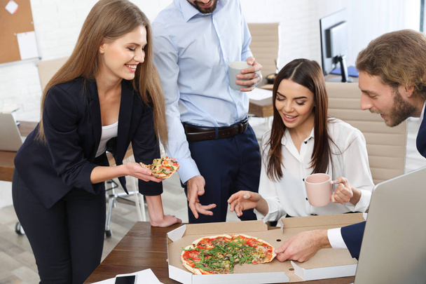 Office employees having pizza for lunch at workplace. Food delivery - 写真・画像