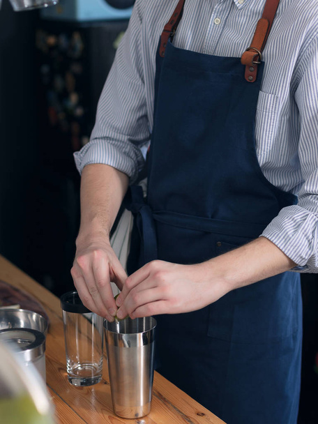 Barman masculin en tablier bleu dans la cuisine préparant un cocktail
 - Photo, image