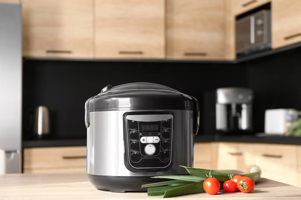 Modern multi cooker and ingredients on table in kitchen - Foto, imagen