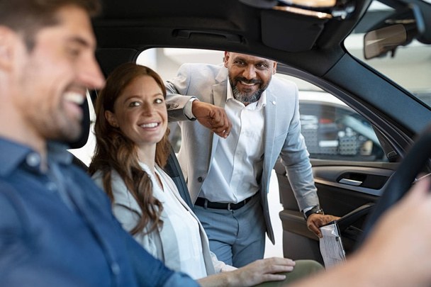 Salesman showing new car to couple - Photo, image