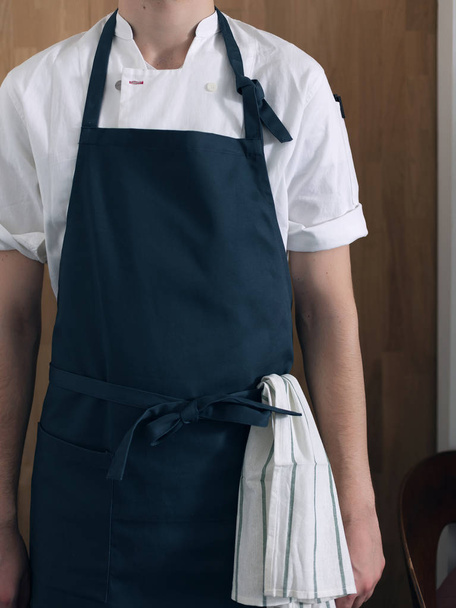 Male cook in blue apron against the background of a wooden wall - Photo, image