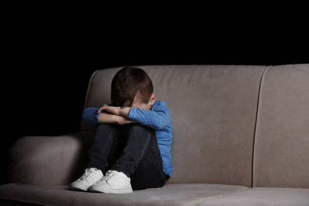 Sad little boy sitting on couch at home, space for text - Foto, afbeelding